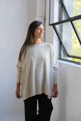 Sweater de punto con hilo lurex color beige, de corte holgado, cuello redondo y mangas largas con puños ajustados. Presenta un diseño con líneas verticales en relieve y aberturas laterales en el ruedo.