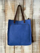 Bolso amplio tipo shopper color azul con textura símil cocodrilo, asas de hombro y bolsillo frontal grande en color marrón.