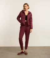 Campera puffer deportiva de mujer, confeccionada en tejido tecnológico ligero con relleno acolchado. Presenta capucha integrada, cierre frontal con cremallera y diseño de manga larga. La prenda destaca por su versatilidad, siendo capaz de transformarse en una pequeña cartera.