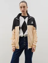 Campera de tela avión con diseño color block en negro y verde, con detalles de franjas blancas en las mangas. Presenta cierre frontal completo, cuello alto, puños y ruedo elásticos, y logo bordado en el pecho.