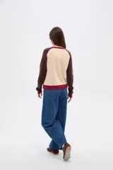 Cardigan de punto con diseño color block, presenta cuerpo en color celeste, mangas en color bordó y detalles de botones y bordes en color rosado. Posee cuello redondo y mangas largas.