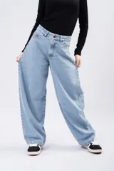 Jean de tiro alto con corte barrel leg, estilo globo, confeccionado en denim de tono azul claro. Presenta costuras reforzadas en la zona de las rodillas y un diseño de pierna ancha que se estrecha sutilmente hacia el tobillo.