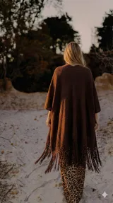 Ruana negra de tejido artesanal con flecos largos en el ruedo, de corte amplio y caída fluida.