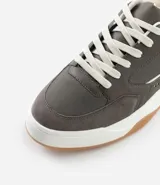 Championes urbanos de estilo street, confeccionados en material sintético color gris oscuro con detalles en blanco. Presentan cierre mediante cordones, recortes laterales decorativos y una suela de plataforma blanca con base color caramelo.