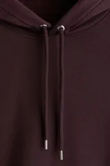 Sudadera con capucha color borgoña, de corte holgado, con cordones ajustables en la capucha y bolsillo canguro frontal.