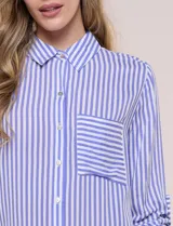 Camisa de corte clásico y silueta relajada con diseño de rayas verticales en azul y blanco, cuello camisero tradicional, cierre frontal con botones y bolsillo aplicado en el pecho con rayas horizontales. Cuenta con mangas largas con presillas para arremangar y ruedo redondeado.