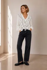 Blusa celeste de manga larga con escote en V y volados en cascada ribeteados en color oscuro. Cuenta con puños elásticos.
