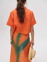 Falda midi tipo pareo color verde con estampado estilo tie-dye en tonos azul, naranja y blanco, con tiras ajustables en la cintura.