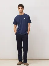 Camiseta de corte regular fit color azul marino, de manga corta y cuello redondo, confeccionada en 100% algodón orgánico, con un pequeño estampado de una cruz blanca en el pecho.