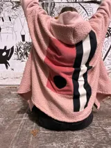 Campera tipo hoodie confeccionada en técnica de collage con texturas combinadas. Presenta cuerpo principal en tejido tipo corderito rosa, con paneles traseros en pana rosa, detalles en franjas verticales blancas y negras, y un aplique circular negro. Incluye capucha integrada.