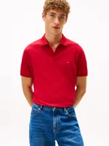 Chomba Tommy Hilfiger de corte regular, color rojo, confeccionada en piqué de mezcla de algodón elástico con tecnología Flex. Cuenta con cuello polo, cierre frontal de dos botones y el logo distintivo de la marca bordado en el pecho.