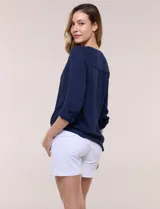 Blusa de calce relajado color salmón, confeccionada en tela liviana con textura sutil. Presenta escote en V con abotonadura frontal, bolsillo parche en el pecho, mangas largas regulables con presilla y ruedo con opción de anudar en el frente.