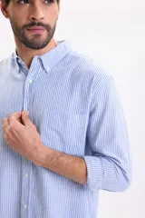 Camisa de lino de manga larga con diseño a rayas en color azul claro y blanco, cuello abotonado y cierre frontal de botones.