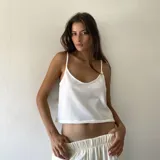 Musculosa básica de corte corto y tirantes finos, confeccionada en tejido acanalado de color blanco. Presenta un diseño minimalista con escote redondeado.