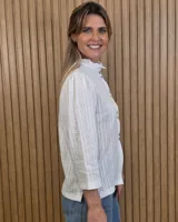 Camisa de algodón color blanco, con cuello alto con volados, mangas tres cuartos con detalles de bordado ingles y cierre frontal con botones de nácar.