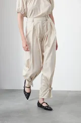 Pantalón baggy negro de silueta relajada con volumen amplio y caída fluida. Presenta detalles de ajuste con hebillas metálicas en el bajo y un cinturón de tela con hebilla metálica en la cintura.