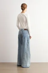 Jean wide leg de tiro medio con diseño bicolor, confeccionado en denim de lavado celeste con detalles de costuras y paneles en contraste. Cuenta con botamanga desflecada.