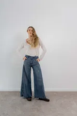 Pantalón de jean color naranja con tiro medio, diseño de pierna ancha y cinco bolsillos. Presenta costuras con pespuntes a contratono.