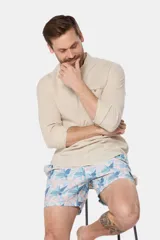 Short de baño celeste con estampado de hojas en tonos rosados y azules, con cintura elastizada.