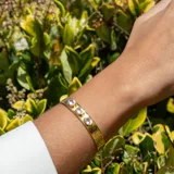 Brazalete rígido dorado con tres piedras ovaladas de cuarzo rosado.