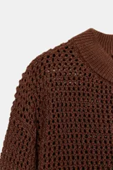 Jersey de manga larga color marrón oscuro, confeccionado en tejido de punto con calados que le otorgan transparencia. Presenta cuello redondo y acabados en rib en puños, cuello y bajo.