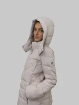 Campera puffer color beige con cierre frontal y bolsillos laterales con cierre. Tiene capucha desmontable y relleno acolchado.