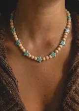 Collar corto de cuentas de madera natural intercaladas con abalorios de cerámica en forma de estrella de color verde menta.