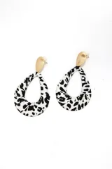 Par de caravanas colgantes con forma de lágrima, con estampado animal print blanco y negro, y pieza superior dorada.