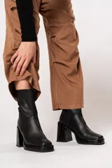 Bota de caña media color negro, de cuero, con horma cuadrada, taco geométrico con textura símil cocodrilo y plataforma.