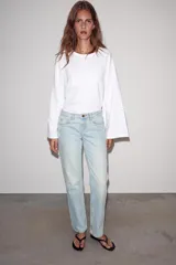 Jeans de mezclilla en color negro gastado, tiro bajo, corte de pernera recta y diseño clásico de cinco bolsillos con cierre frontal de cremallera y botón metálico.