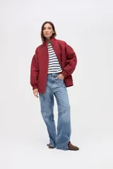 Campera bomber de gabardina con diseño capitoneado, cuello alto, cierre frontal con botones a presión y mangas con puños elásticos.