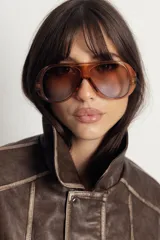 Lentes de sol estilo aviador con armazón de policarbonato en tono ámbar translúcido y cristales degradados en tonos marrones. Cuentan con protección UV400.