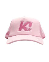Gorra tipo trucker color rosa con panel frontal de espuma y paneles traseros de malla. Presenta un bordado frontal con la letra K y una estrella, además de un detalle bordado en el lateral.