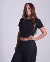 Remera de morley de algodón, color negro, con cuello redondo, mangas cortas y terminaciones con borde fruncido.