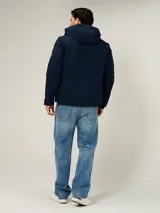 Campera soft shell Tommy Hilfiger color azul marino, con capucha, cierre frontal de cremallera con detalles tricolores y bolsillos con cierre en los laterales y en el pecho.