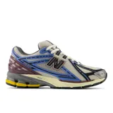 Championes New Balance modelo 1906R, de color beige con detalles en azul, negro, gris y amarillo.