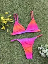 Conjunto de bikini con corpiño triangular fijo y bombacha colaless regulable, con estampado degradado en tonos naranja, rosado y violeta.