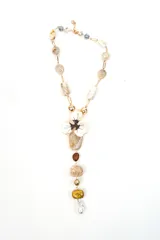 Collar largo con cadena dorada, cuentas de piedra en tonos beige y marrones, y un dije colgante en forma de flor blanca y marrón con cuentas adicionales.