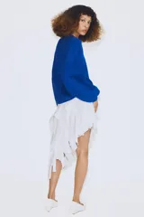 Jersey de punto color azul, con cuello redondo, mangas largas amplias y costuras marcadas en el frente.