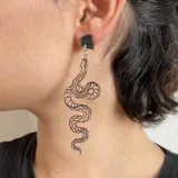 Par de aros colgantes con forma de serpiente plateada con detalles en negro.
