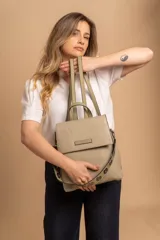 Mochila cartera de diseño versátil con tapa frontal, confeccionada en material símil cuero con textura granulada. Cuenta con doble compartimento, división interna, cierre de seguridad y bolsillo trasero con cierre. Incluye correas ajustables y una correa decorativa con ojales metálicos.