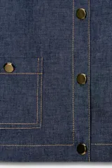 Blazer corto de denim azul oscuro, estilo chaqueta, con cuello redondo, manga larga y cierre frontal de botones dorados. Presenta dos bolsillos de parche con solapa y botón dorado en el frente.