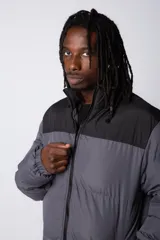 Campera puffer de diseño bicolor, con cuerpo en tono beige y canesú superior en color negro. Presenta cuello alto, cierre frontal completo y puños elásticos.