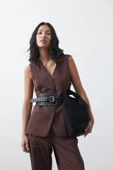 Chaleco sastrero de color marrón, con silueta recta, escote en V y cierre frontal con botones. Presenta una estructura definida y tejido con caída firme.