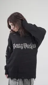 Buzo de punto negro con diseño de estilo desgastado y roturas en mangas y ruedo. Presenta una estampa frontal con tipografía gótica en color gris.