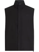 Chaleco negro Calvin Klein con cuello alto, cierre de cremallera, bolsillos laterales, bajo con cordón ajustable y logo tonal en el pecho.