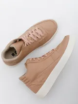 Botín de cuero color nude, con caña alta, cordones y suela blanca.