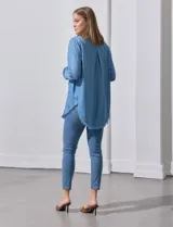 Camisa celeste de tencel, marca Hester & Orchand. Tiene cuello con solapa, escote en V, abertura central con botones, bolsillo aplicado en el frente y ruedo desflecado.