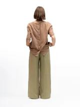 Remera de lino con corte holgado, cuello redondo y mangas cortas. Presenta un diseño minimalista con detalle de botones en la espalda.