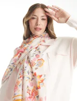 Pashmina estampada con diseño floral multicolor sobre fondo blanco, con terminación deflecada en los bordes.